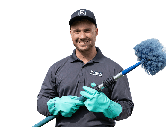 Hawx pest control technician treating a home exterior
