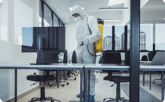 Pest control technician in protective suit treating an office