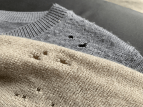Close-up of two sweaters eaten by moths
